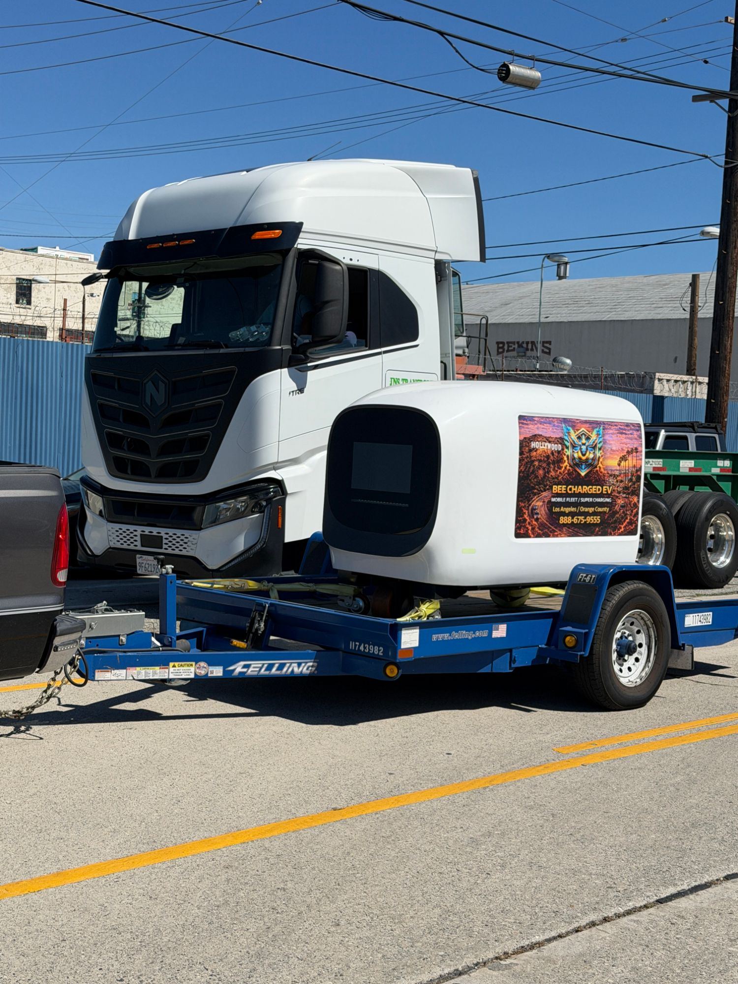 Trailer-mounted mobile DC charging pod parked beside a white Class 8 electric semi tractor on a city street